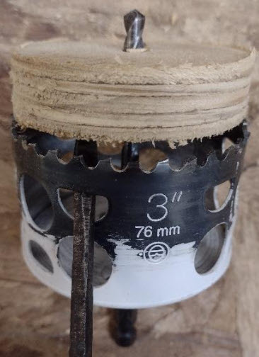Wood cut out being removed from hole saw.